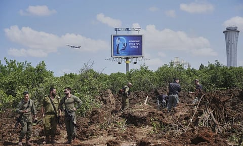 Israeli security forces inspect the site where the Israeli military said a projectile fired by Yemen's Houthi rebels landed in the area of Ben Gurion International Airport near Tel Aviv (AP)