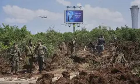 Israeli security forces inspect the site where the Israeli military said a projectile fired by Yemen's Houthi rebels landed in the area of Ben Gurion International Airport near Tel Aviv (AP)