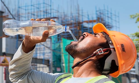 A worker drinks water to quench his thirst during a hot summer day, at a construction site, in Gurugram (PTI)
