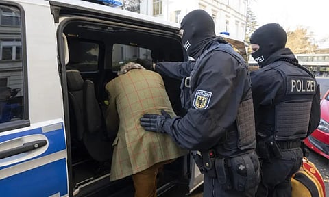  Masked police officers lead the arrested suspect Heinrich XIII Prince Reuss, left, to a police vehicle during a raid against so-called ‘Reich citizens’ in Frankfurt, Germany (AP)