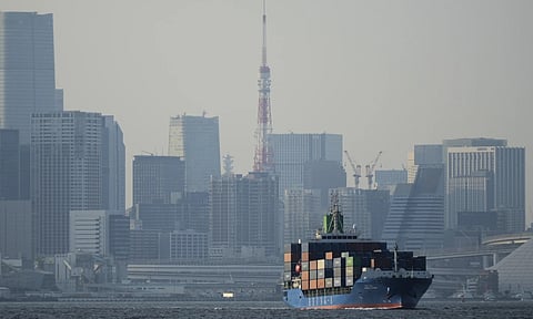 Tokyo Tower is seen amid tall buildings as a container ship leaves a cargo terminal in Tokyo, (AP)