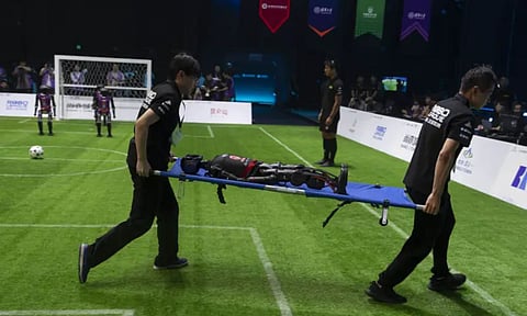 Workers carry out a T1 robot from Booster Robotics during the inaugural RoBoLeague robot soccer competition held in Beijing (AP Photo)