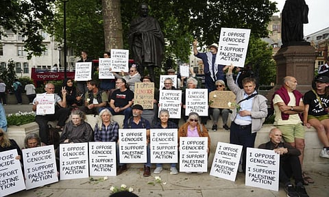 People take part in a protest in support of 'Palestine Action', organised by the Defend Our Juries group, in front of the Mahatma Gandhi statue in Parliament Square in London (AP)
