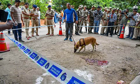 Police and security personnel with a sniffer dog stand guard at a cordoned area where CPI leader K Chandu Naik was shot dead (PTI) 