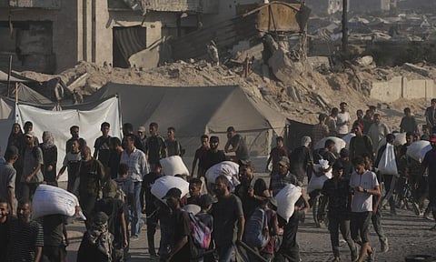 Palestinians carry sacks of flour unloaded from a humanitarian aid convoy that reached Gaza City from the northern Gaza Strip (AP)