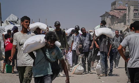 Palestinians carry sacks of flour unloaded from a humanitarian aid convoy that reached Gaza City from the northern Gaza Strip (AP Photo)