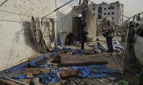 Palestinian inspect the destroyed tent where journalists, including Al Jazeera correspondents Anas al-Sharif and Mohamed Qureiqa (AP)