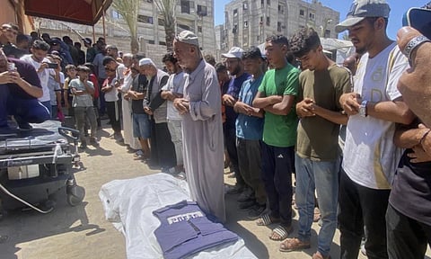 In this family handout photo, Riyad Dagga, center, and other relatives and friends pray over the body of his daughter, freelance journalist Mariam Dagga, 33, during her funeral after she was killed in a double Israeli strike on Nasser Hospital in Khan Younis, southern Gaza Strip (AP)