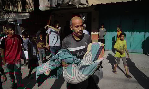 A Palestinian man carries the body of Hassan Nasr, 12, who was killed by an Israeli military strike in Zawaida, central Gaza Strip, Thursday, Sept. 25, 2025. AP/PTI
