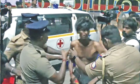 Police personnel protecting an ambulance driver from TVK cadre’s attack in Karur on September 27