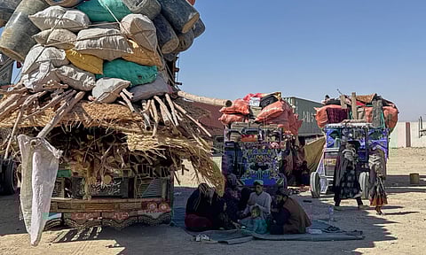 Afghan refugees sit next to their belongings loaded onto vehicles as they wait for opening of the border crossing point, which closed following Afghan and Pakistani security forces exchanged cross border firing, at a camp in Charnan, Pakistan, Sunday, Oct. 12, 2025. (AP Photo)