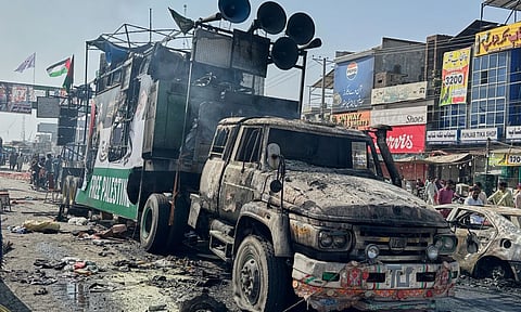 Local residents stand by burnt vehicles after police in Pakistan clashed with thousands of protesters during a march in support of Palestinians, in Muridke near Lahore, Pakistan (Photo: AP)