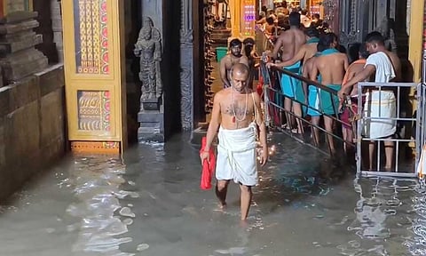 Devotees wade through rain water that entered the Tiruchendur temple on Thursday 