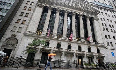 A woman with an umbrella passes the New York Stock Exchange (Photo: AP)