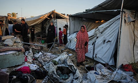 Displaced Palestinians inspect the damage after an Israeli army strike on their tent camp in Deir al-Balah, Gaza Strip (AP)