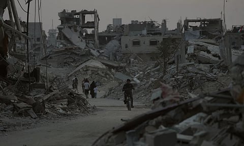 Displaced Palestinians walk among the ruins of destroyed buildings in Khan Younis, Gaza Strip (AP)