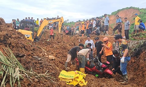 Rescuers remove a scooter buried in the mud as they search for victims at a village hit by a landslide in Batu Goading, North Sumatra, Indonesia (AP)