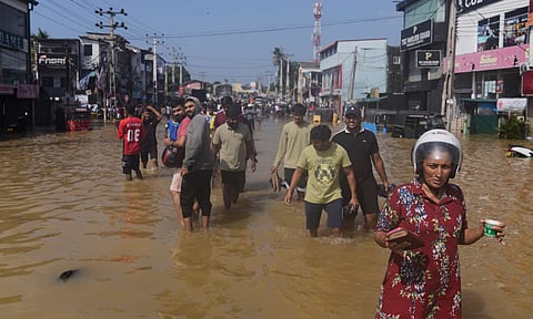 People wade through a submerged area of Colombo, Sri Lanka, following flooding on Sunday (AP) 