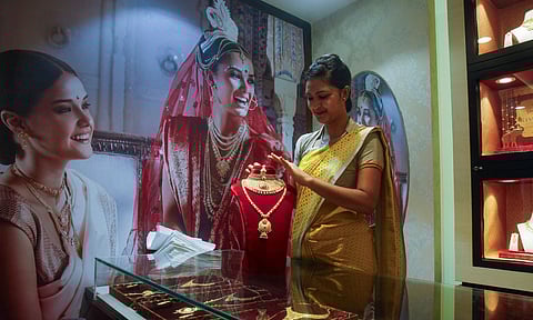 A woman sells gold jewellery in a shop.