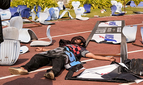 A person lays amidst broken chairs following chaos during an event of Argentine footballer Lionel Messi as part of his 'G.O.A.T. India Tour 2025', at Vivekananda Yuba Bharati Krirangan (VYBK), in Kolkata, Saturday, Dec. 13, 2025. Fans protested after failing to catch a clear glimpse of the footballer despite paying hefty sums for tickets. (PTI) 