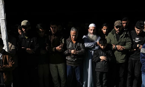Palestinians pray during the funeral of Hamas' Al-Qassam Brigades operatives, whose bodies are draped in the group's flag, killed in an Israeli strike Saturday, in Gaza City (AP)