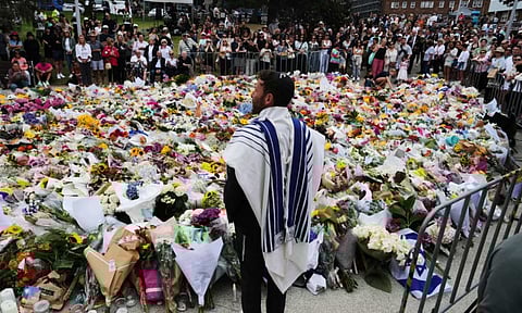 Rabbi Yossi Friedman speaks to people gathering at a flower memorial by the Bondi Pavilion at Bondi Beach on Tuesday, following Sunday's shooting in Sydney, Australia. (AP)