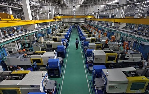 Employees work on machines used to make auto parts at the factory