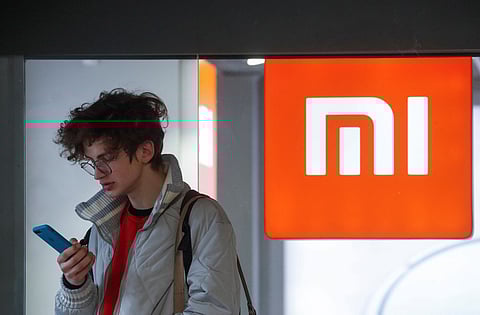 A man uses his smartphone next to the Xiaomi brand's store