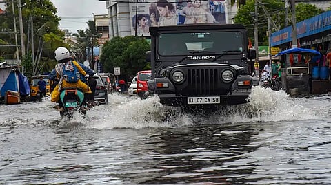 Vehicles wade through a waterlogged road in Kochi