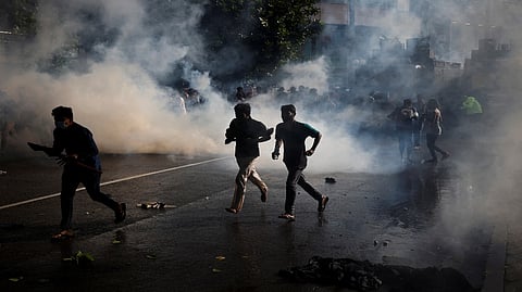 Protestors run for cover as police use tear gas during a protest