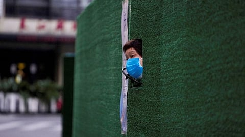 A resident looks out through a gap in the barrier at a residential area during lockdown, amid the coronavirus disease (COVID-19) pandemic, in Shanghai
