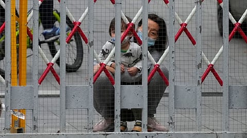 A resident and a child look out through gaps in the barriers at a closed residential area during lockdown, amid the coronavirus disease (COVID-19) pandemic, in Shanghai, China