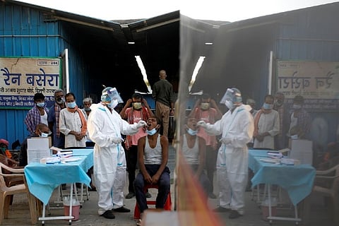 A healthcare worker collects a coronavirus disease (COVID-19) test swab sample from a man as others watch, at a temporary shelter for the homeless in New Delhi