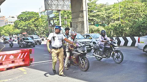 A cop stops a two-wheeler where the pillion rider is helmet-less