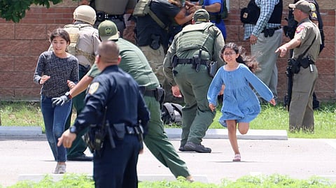 Children run to safety after escaping from a window during a mass shooting at Robb Elementary School