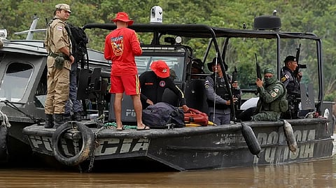 Police officers and rescue team members stand on a boat during the search operation for British journalist