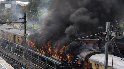 Smoke billows out from a passenger train coach after it was set on fire by protestors during a protest against Agnipath scheme