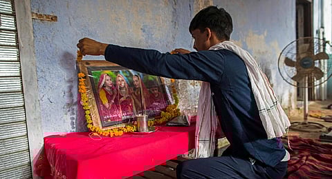 A man places a garland over the portrait of the three married sisters, who were all found dead in a well on May 28 in Rajasthan