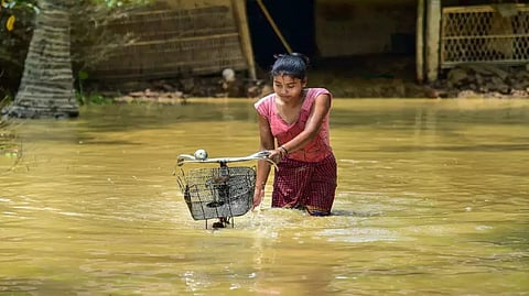 A girls pushes her bicycle as she wades through a flood-affected area in Assam