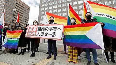 Plaintiffs' lawyers and supporters hold rainbow flags and a banner that reads: "Unconstitutional judgment" outside Sapporo District Court