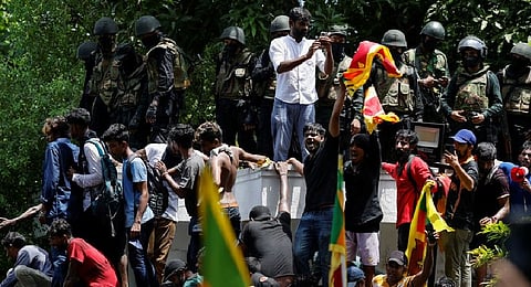 Demonstrators stand on the wall of Sri Lanka's Prime Minister Ranil Wickremesinghe's office premises