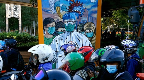 Motorcycle riders are seen near a mural promoting awareness of the coronavirus disease