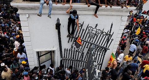 Demonstrators shout slogans and wave Sri Lankan flags during an anti-government protest inside the office building of Sri Lanka's PM