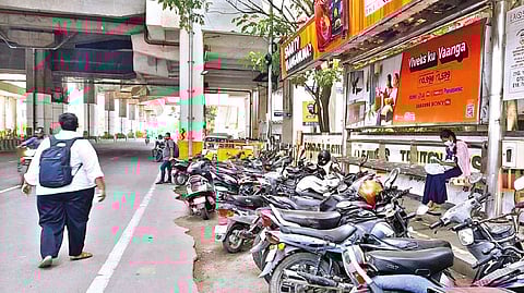 Two-wheelers parked in front of a bus stand near Meenambakkam Metro station