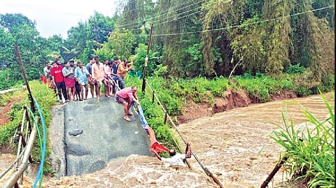 Villagers rescuing a daily wager trapped in the gushing waters following collapse of a causeway in Gudalur on Wednesday.