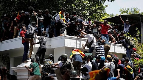 Protestors climb the front gate of Ranil Wickremesinghe's office during a protest in Colombo on July 13