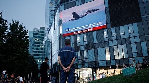 A man watches a CCTV news broadcast, showing a fighter jet during joint military operations near Taiwan by the Chinese's PLA, at a shopping center in Beijing