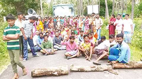 Villagers, including women blocking the road with the body