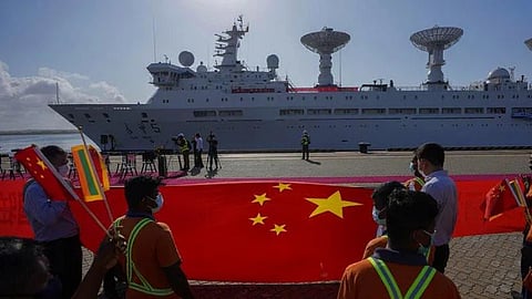 Sri Lankan port workers hold a Chinese national flag to welcome Chinese research ship Yuan Wang 5 as it arrives in Hambantota International Port in Hambantota, Sri Lanka.