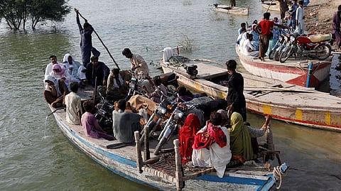 Residents use boats to transport their belongings as they head to their village, following rains and floods during the monsoon season in Sehwan, Pakistan